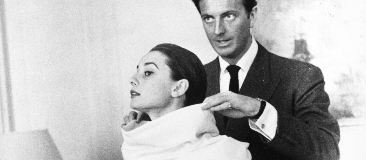 Fashion designer Hubert Givenchy adjusts a scarf on actress Audrey Hepburn during a fitting in Rome, Italy, on April 26, 1958.