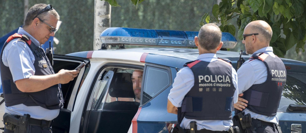 Varios mossos d'esquadra vigilan a un hombre detenido tras el asesinato de una mujer a cuchilladas en el municipio gerundense de Maçanet de la Selva