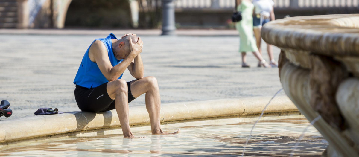 Un hombre se refresca en una fuente en Sevilla