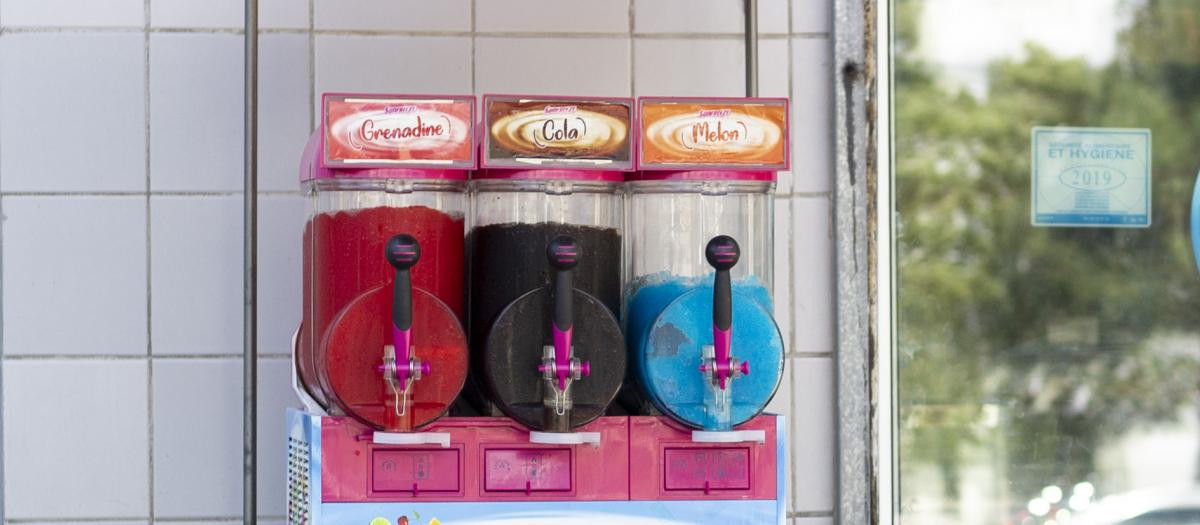 Un comercio francés con una máquina de venta de granizados en su exterior y la puerta abierta
