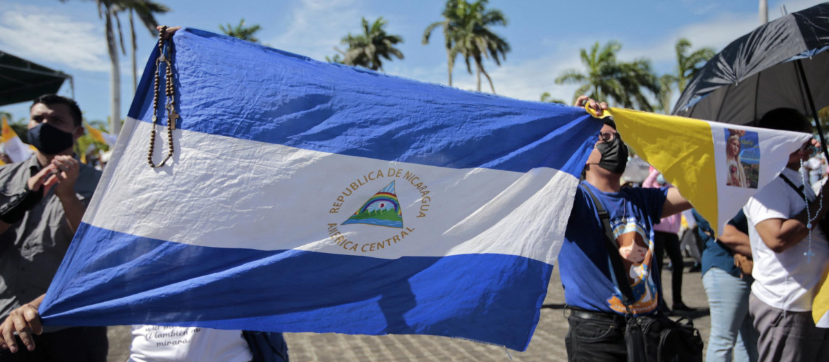 Católicos sujetan una bandera nicaragüense en la procesión de la Virgen de Fátima en los aledaños de la catedral de Managua, 13 de agosto de 2022