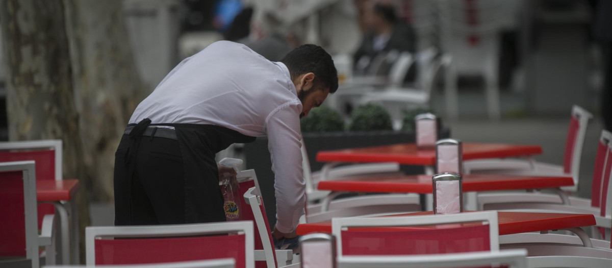 Un camarero limpia las mesas de un bar en Sevilla (Andalucía, España).