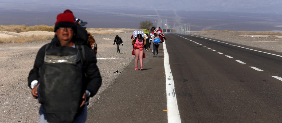 Inmigrantes, en su mayoría venezolanos, caminan por el arcén de una carretera después de cruzar a Chile desde la frontera con Bolivia, cerca de Colchane, Chile, el sábado 6 de febrero de 2021