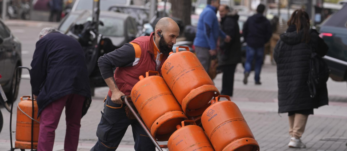 Un trabajador carga con bombonas de butano en Madrid, España