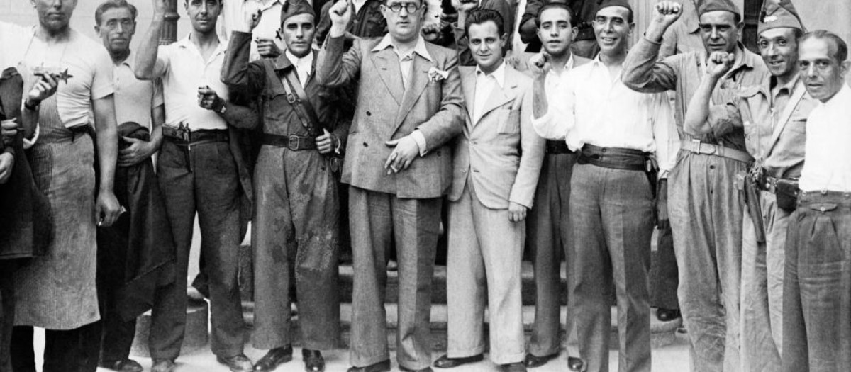 El jefe de la Milicia Popular de Investigación, Agapito García Atadell, (con gafas), saluda puño en alto acompañado de algunos de los milicianos que trabajan a sus órdenes
