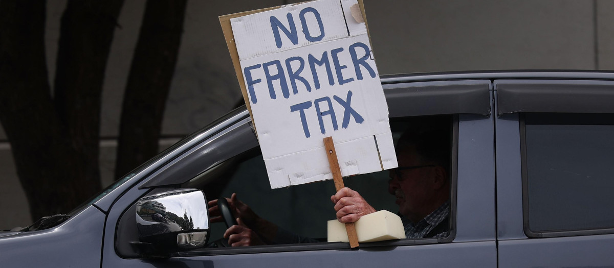Un hombre muestra un cartel durante una protesta contra los planes del Gobierno de Nueva Zelanda de gravar las emisiones de los animales de granja, en Wellington, el 20 de octubre de 2022