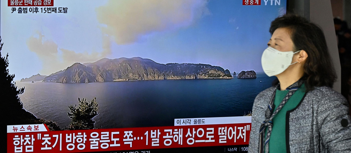 A woman walks past a television screen showing a news broadcast with live footage of the island of Ulleungdo at a railway station in Seoul on November 2, 2022. - South Korea on November 2 told residents on the island of Ulleungdo off its east coast to evacuate to bunkers after North Korea fired three short range ballistic missiles. (Photo by JUNG YEON-JE / AFP)
