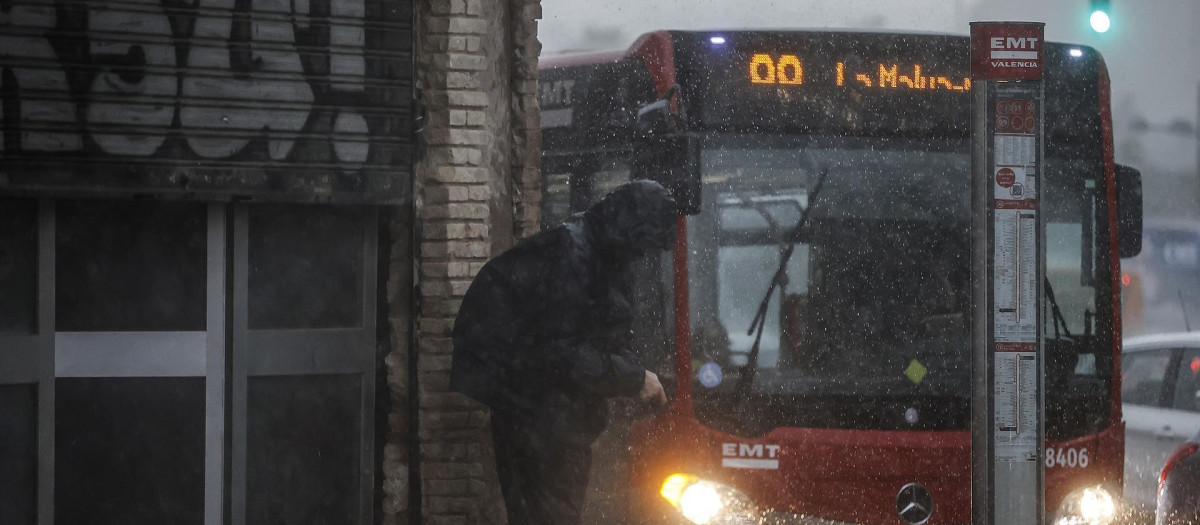 Una persona se protege de la lluvia con la capucha de su chaqueta, en Valencia.