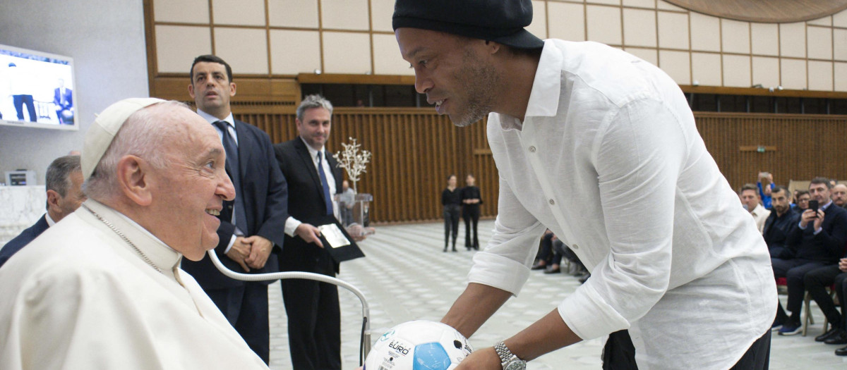 Former Brazilian player Ronaldinho hands a football to Pope Francis during an audience to participants to a friendly tribute "match for peace" in memory of late Argentininan player Diego Maradona, on November 14, 2022 at Paul-VI hall in The Vatican. - The match is organised by "WePlayForPeace", a foundation set up by Pope Francis. (Photo by Handout / VATICAN MEDIA / AFP) / RESTRICTED TO EDITORIAL USE - MANDATORY CREDIT "AFP PHOTO / VATICAN MEDIA" - NO MARKETING NO ADVERTISING CAMPAIGNS - DISTRIBUTED AS A SERVICE TO CLIENTS