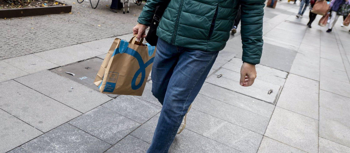Un hombre camina con una bolsa con compra de un centro comercial