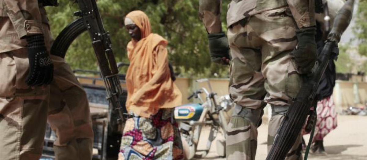 Una mujer pasea frente a unos militares en Gwoza, ciudad liberada por el ejército nigeriano en 2015.