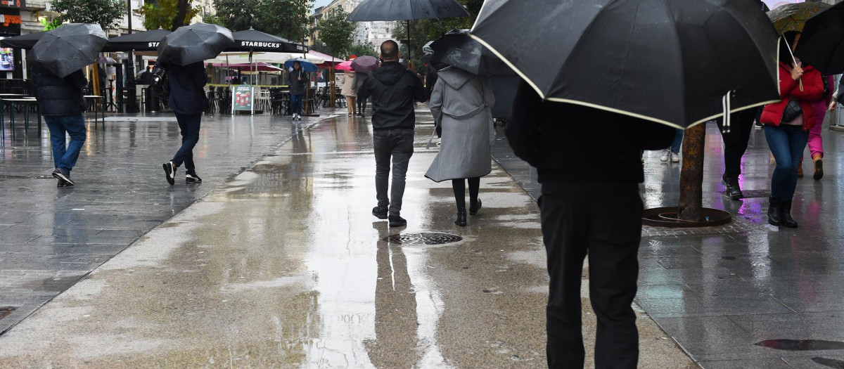 Personas caminan por la calle con paraguas, a 13 de diciembre de 2022, en Madrid