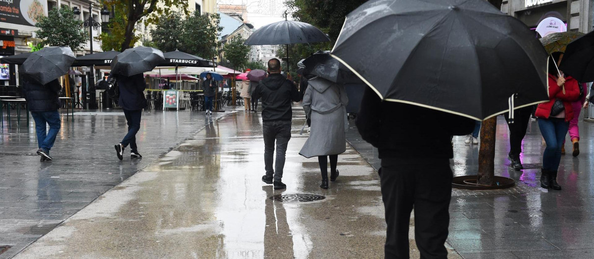 Personas caminan por la calle con paraguas, a 13 de diciembre de 2022, en Madrid