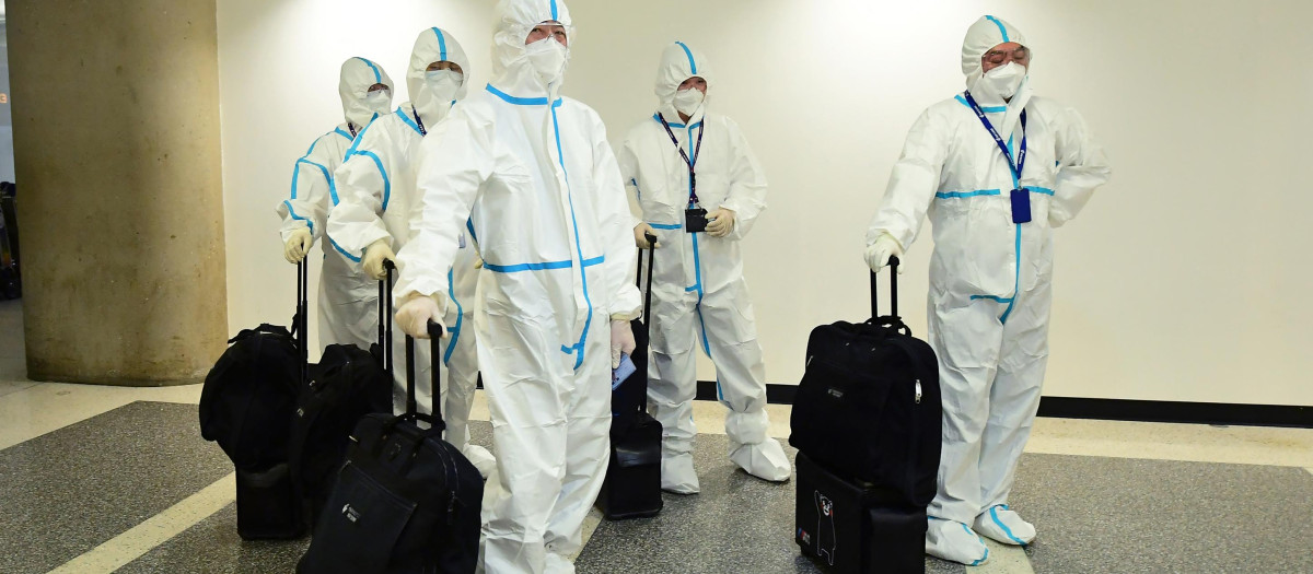 La tripulación de cabina de Air China llega al aeropuerto de Los Ángeles equipada con un traje EPI