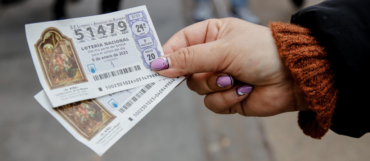 Una mujer sostiene dos décimos para el Sorteo Extraordinario del Niño, a 2 de enero de 2023, en Madrid