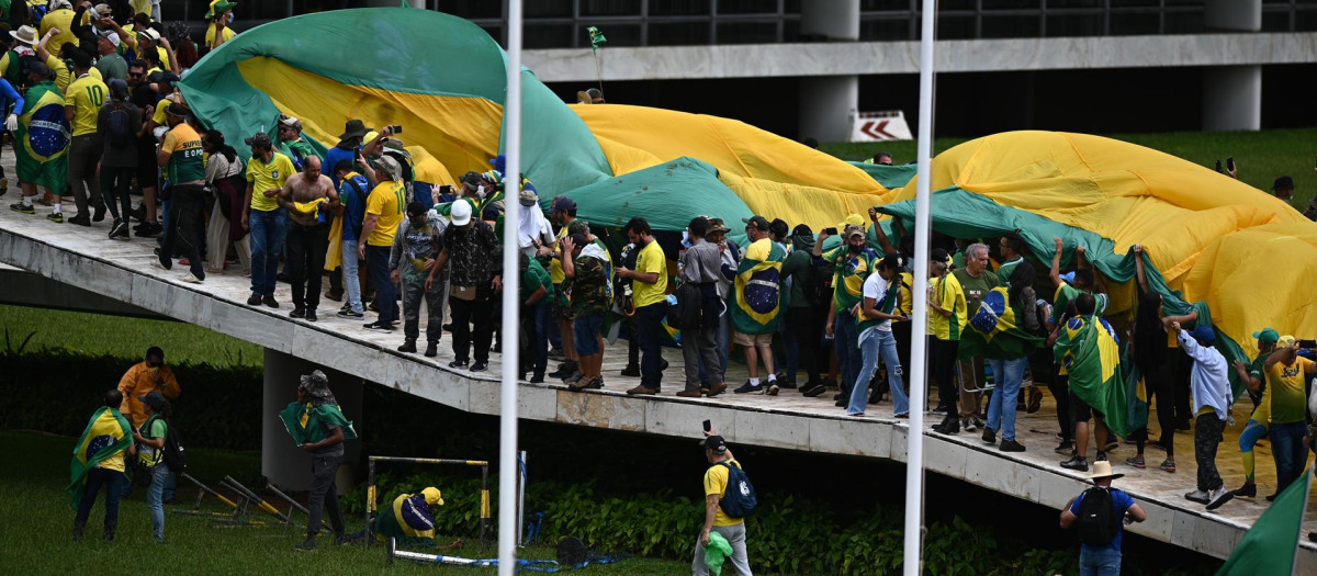 Manifestantes portan una gran bandera de Brasil en su asalto al Congreso