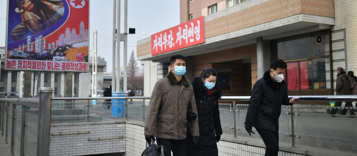 Varias personas protegidas por mascarilla caminan por una calle de Pionyang este domingo