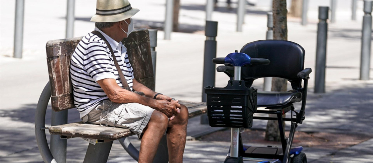 Un anciano con mascarilla sentado en un banco.