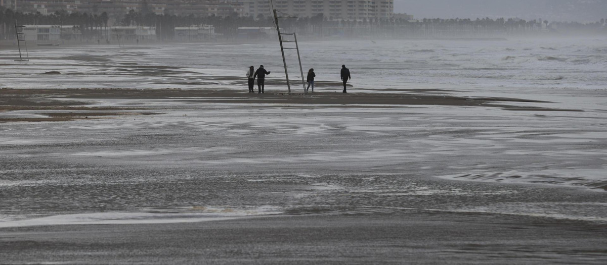 Cuatro personas pasean por la playa de la Malvarrosa cuando la Aemet ha establecido para este martes la alerta naranja en las tres provincias de la Comunitat, por fenómenos costeros en el litoral de Valencia y la costa norte de Alicante, y por nieve y precipitaciones de hasta 100 litros por metro cuadrado en el interior de Castellón. EFE/Manuel Bruque