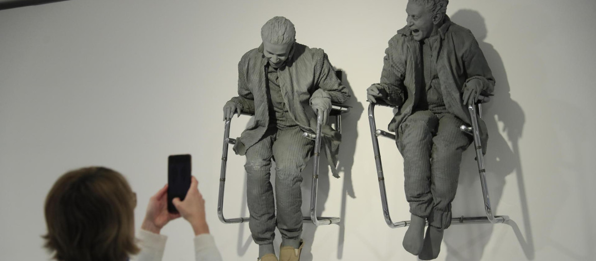 'Una mujer fotografía la obra de Juan Muñoz 'Dos sentados en el muro'