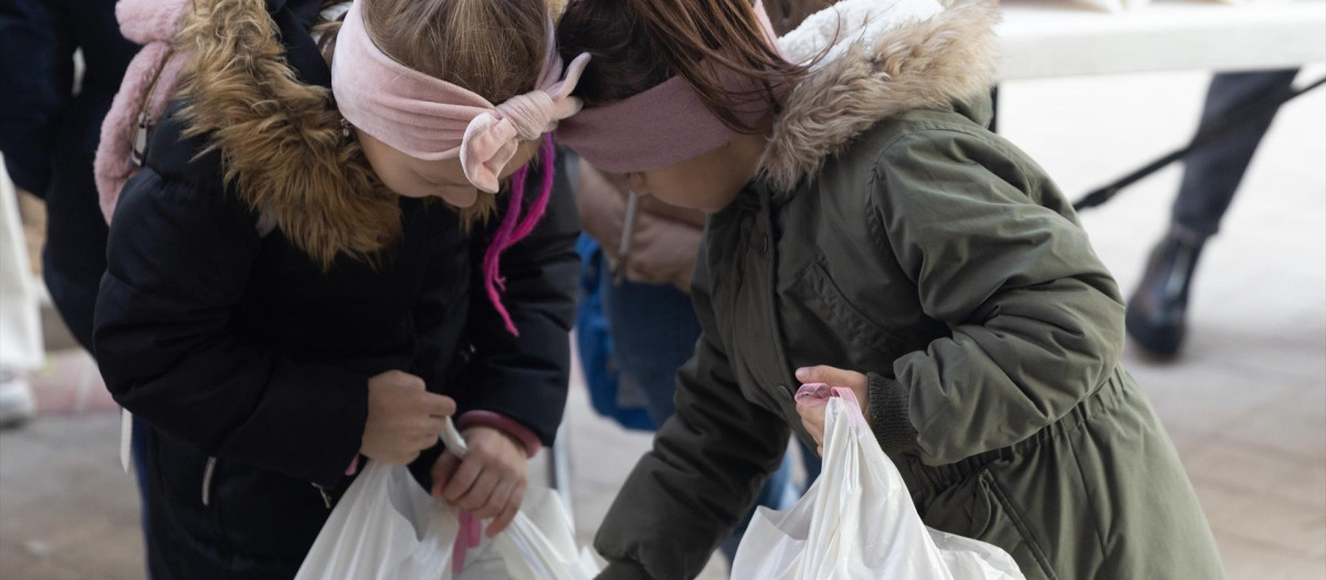 Dos niñas ucranianas refugiadas reciben bolsas con regalos en la Plaza San Amaro, en diciembre de 2022