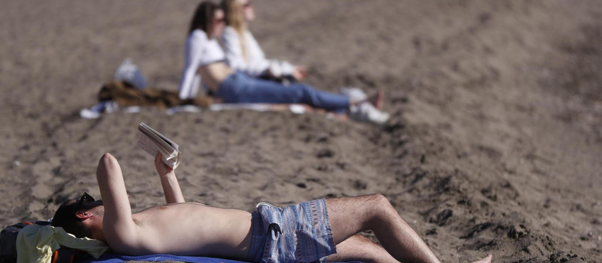 Varias personas toman el sol en la playa de la Malagueta