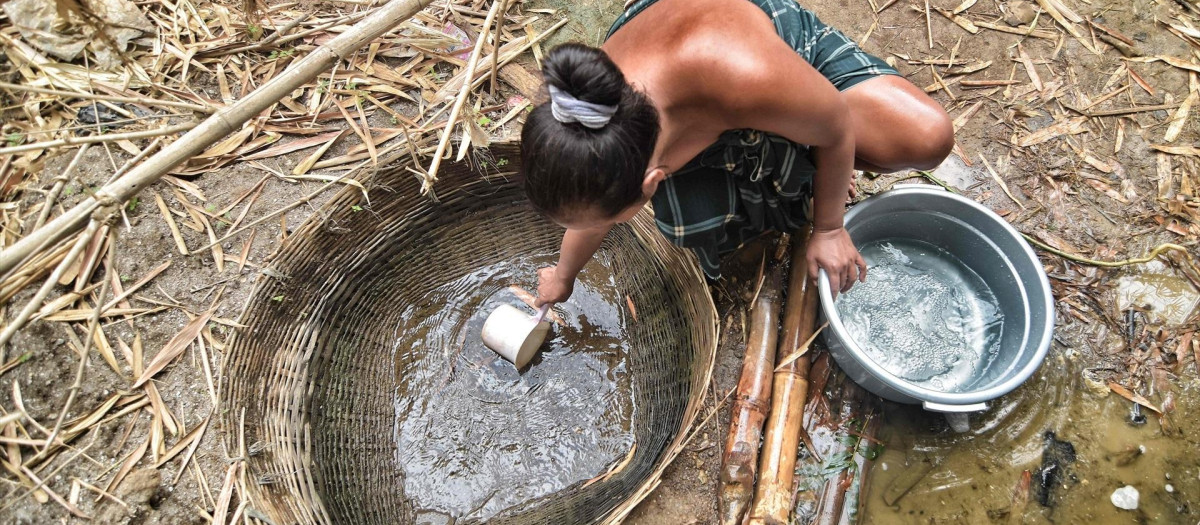 Una mujer recoge agua de un pozo en el río Cihoe