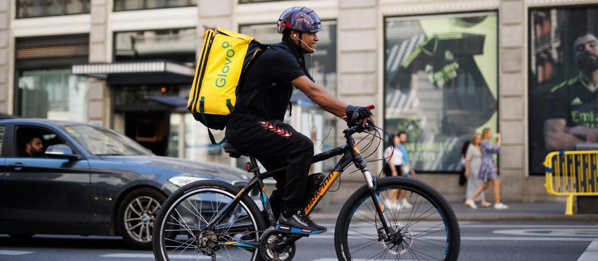Un repartidor de Glovo en bicicleta por una calle del centro de Madrid.