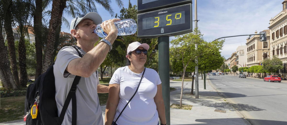 Un hombre bebe agua el pasado viernes en Murcia junto a un termómetro que marca 35 grados