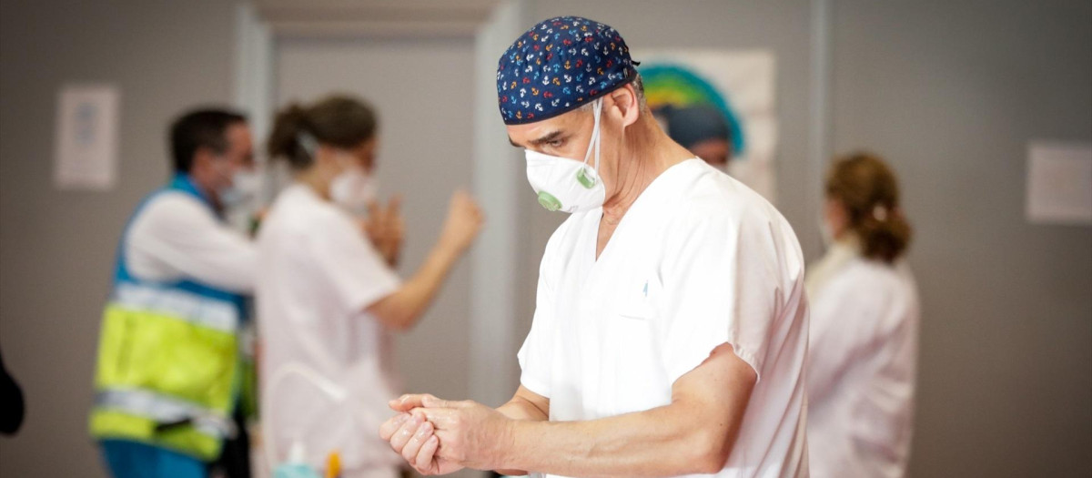 Un sanitario con mascarilla se desinfecta las manos