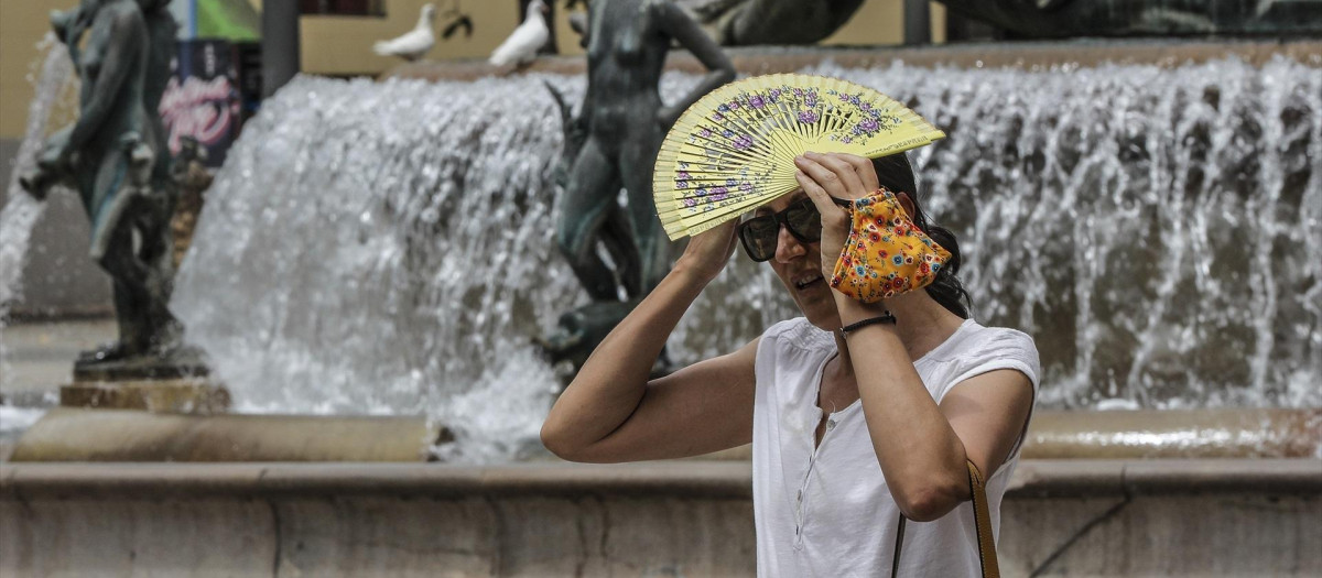 Una mujer se tapa la cabeza con un abanico para guarecerse de las altas temperaturas