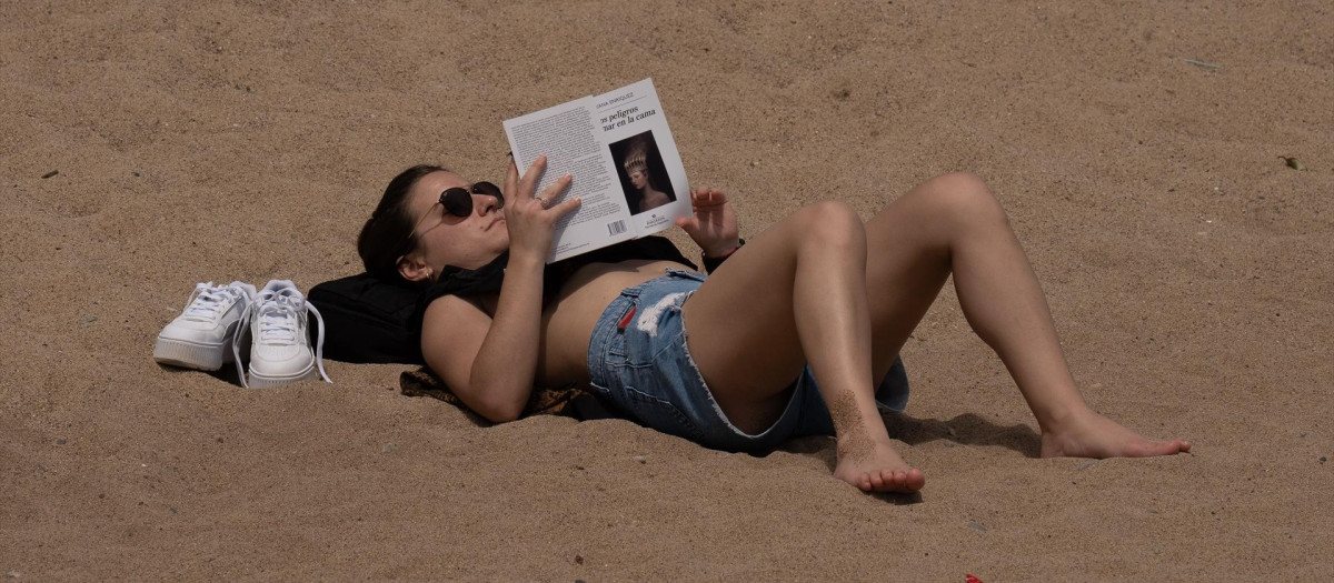 Una mujer toma el sol en la playa de la Barceloneta