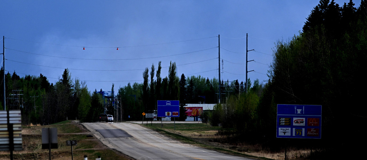 Una pequeña columna de humo se ve a lo lejos por un control policial en las afueras de la ciudad de Drayton Valley, Alberta, Canadá