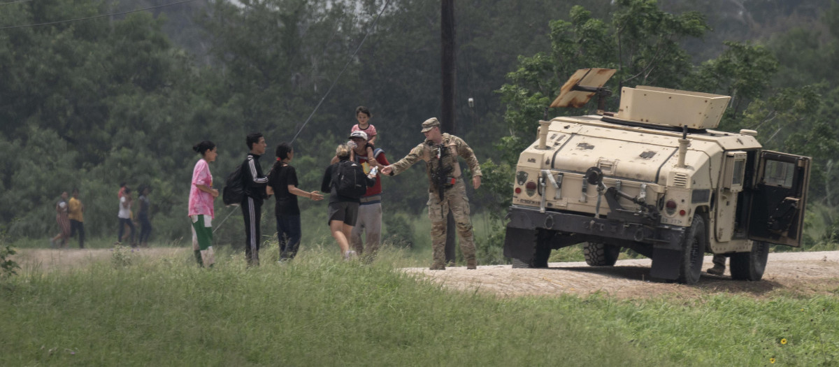 Migrants are given water by a member of the US military after they crossed into the United States from Mexico, in Brownsville, Texas, on May 11, 2023. - The US on May 11, 2023, will officially end its 40-month Covid-19 emergency, also discarding the Title 42 law, a tool that has been used to prevent millions of migrants from entering the country. (Photo by Andrew CABALLERO-REYNOLDS / AFP)
