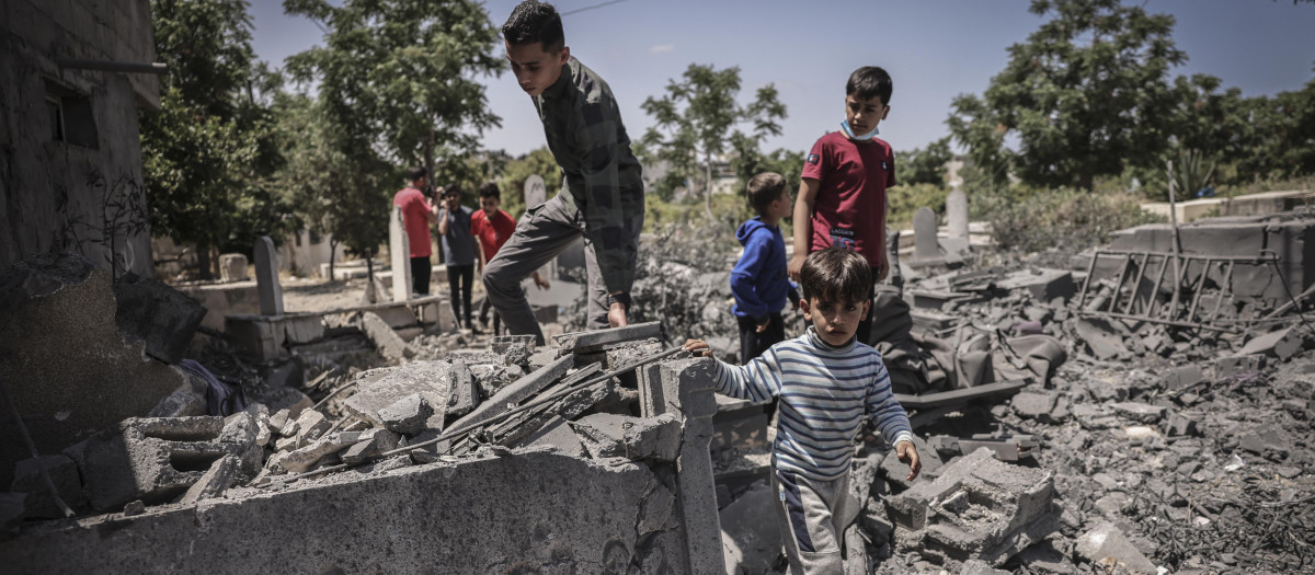 People inspect the damage in a graveyard hit by an Israeli air strike in Beit Lahia in the northern Gaza Strip, on May 13, 2023. Israeli air strikes battered Gaza again on May 13 in response to rocket fire from militants as deadly fighting resumed after a night of relative calm, despite efforts to secure a truce. (Photo by MOHAMMED ABED / AFP)