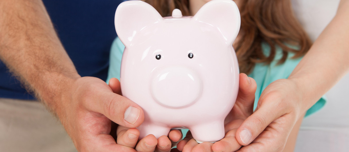 Una familia sujeta una hucha con forma de cerdo