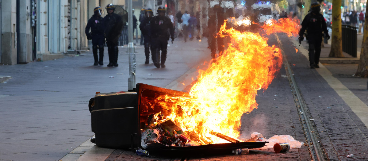 Policías antidisturbios franceses montan guardia detrás de un basurero quemado en Marsella