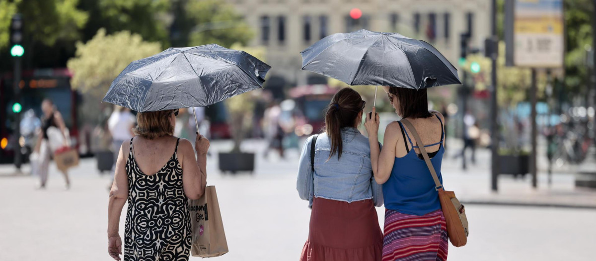 Tres mujeres se protegen del calor con unos paraguas