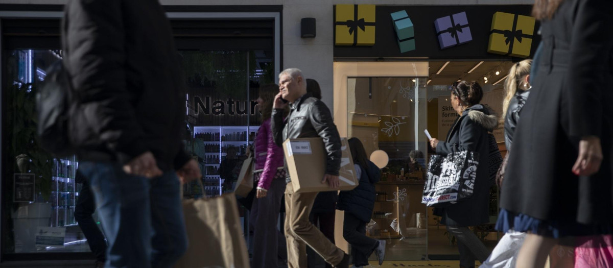 Varias personas con bolsas de la compra en una calle de Sevilla.
