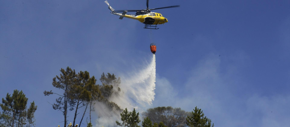Un helicóptero arroja agua sobre un incendio forestal