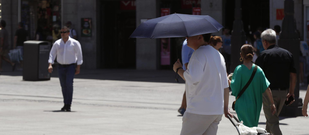 Un hombre se protege del sol con un paraguas en Madrid