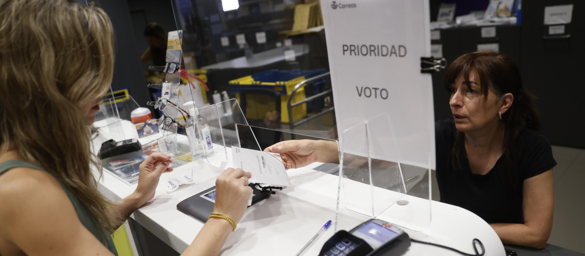 Una electora entrega su voto en una oficina de Correos