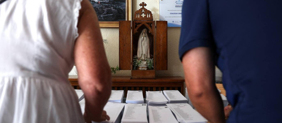 La gente recoge papeletas para votar el día de las elecciones generales anticipadas en un colegio electoral.