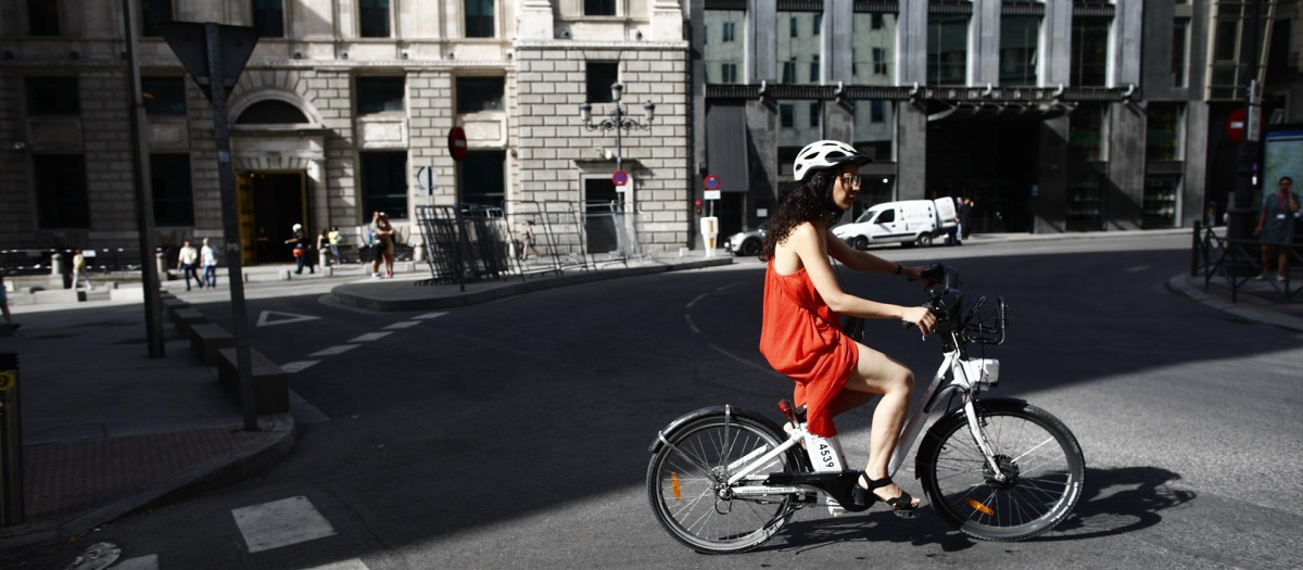Una ciclista pasea con una bicicleta eléctrica cerca del Congreso de los Diputados.