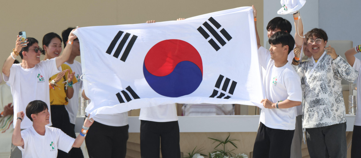 Pilgrims celebrate on stage holding a South Korean flag, as the next WYD are to be held in Seoul, during the closing mass of the World Youth Days (WYD) in Tejo Park, Lisbon, on August 6, 2023. Around one million pilgrims from all over the world will attend the World Youth Day, the largest Catholic gathering in the world, created in 1986 by John Paul II. (Photo by Thomas COEX / AFP)