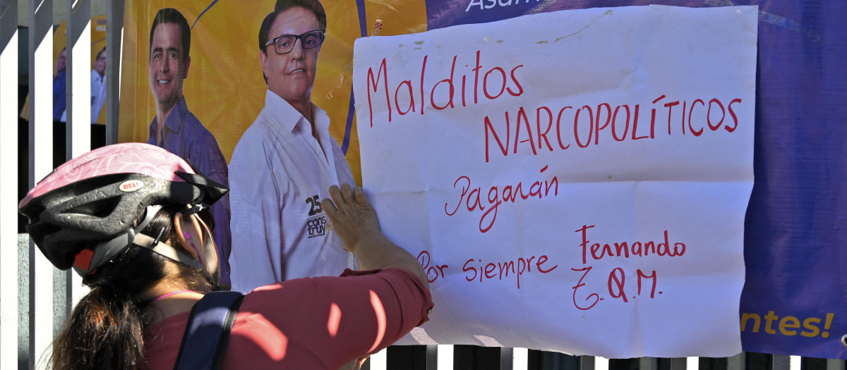 Un ciclista cuelga una pancarta en las rejas del complejo deportivo donde la víspera fue asesinado el candidato presidencial ecuatoriano Fernando Villavicencio