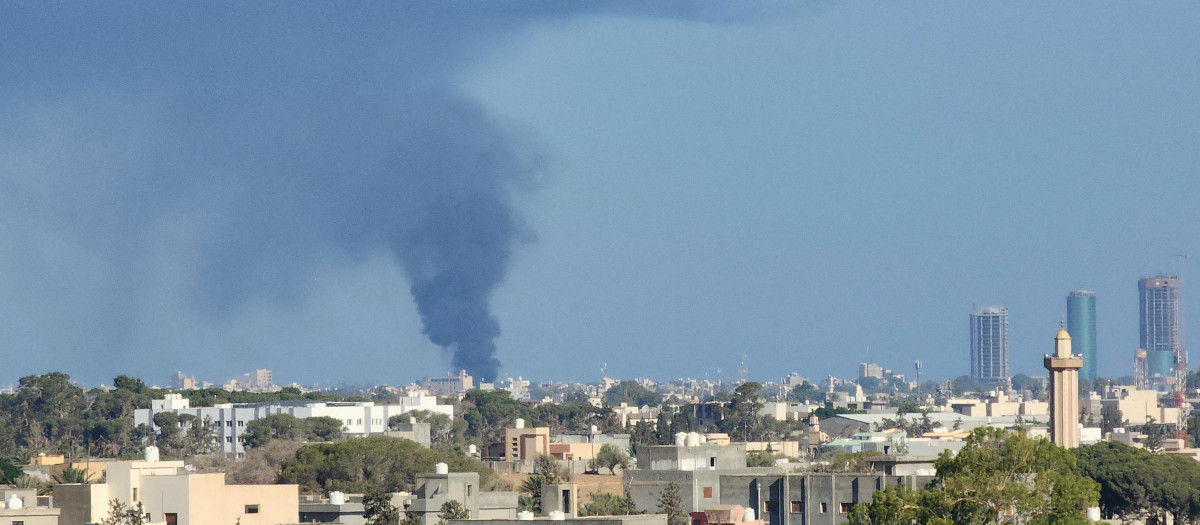 Una columna de humo se eleva al cielo de la capital de Libia en medio de combates entre milicias
