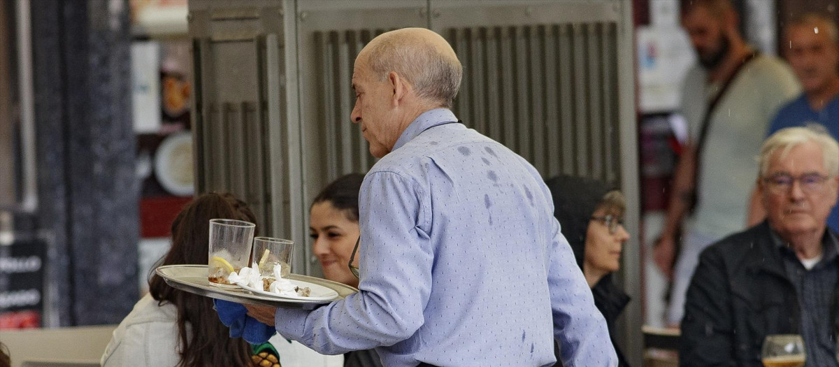 Un camarero porta una bandeja en una terraza de un bar de Madrid.