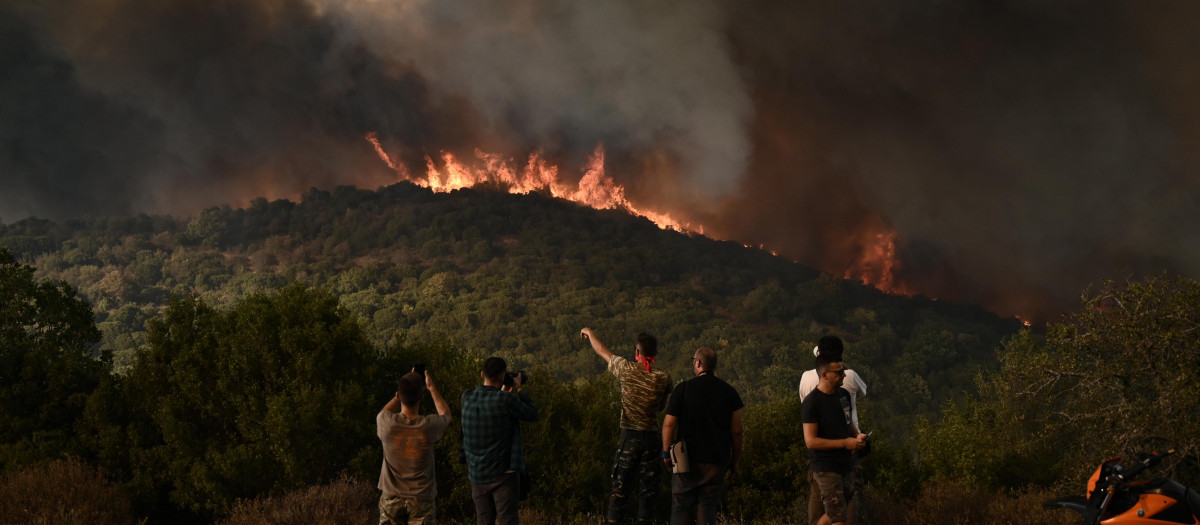 La gente observa el incendio forestal que arrasa un bosque en Sikorahi, cerca de Alexandroupoli, al norte de Grecia