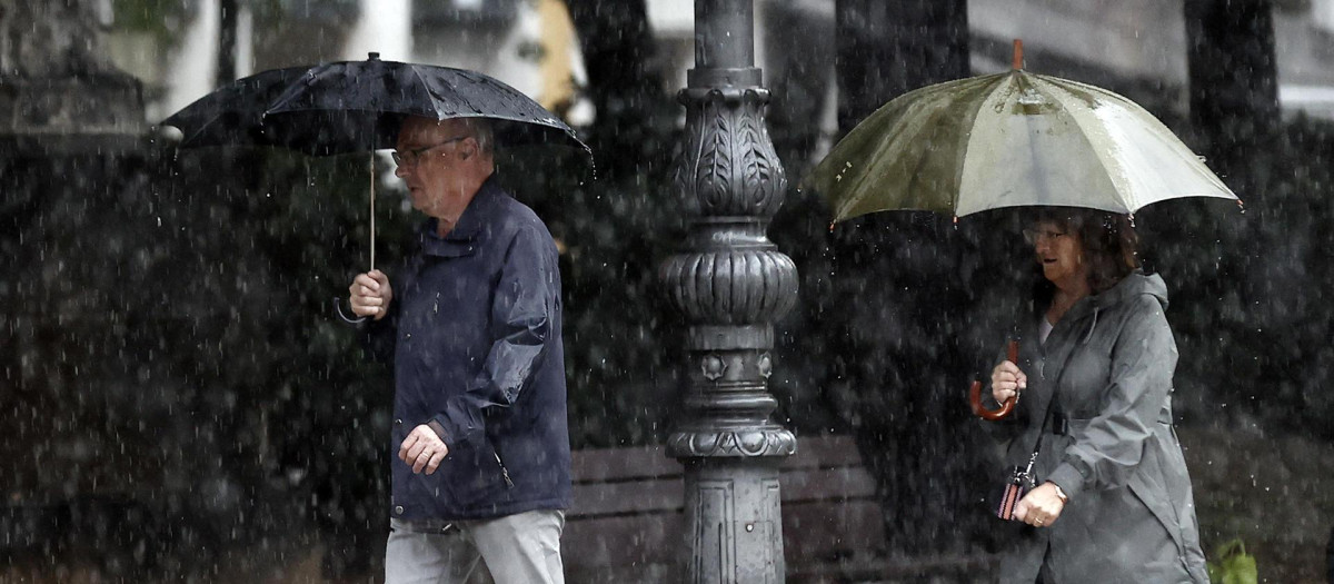 Dos personas se protegen de la lluvia